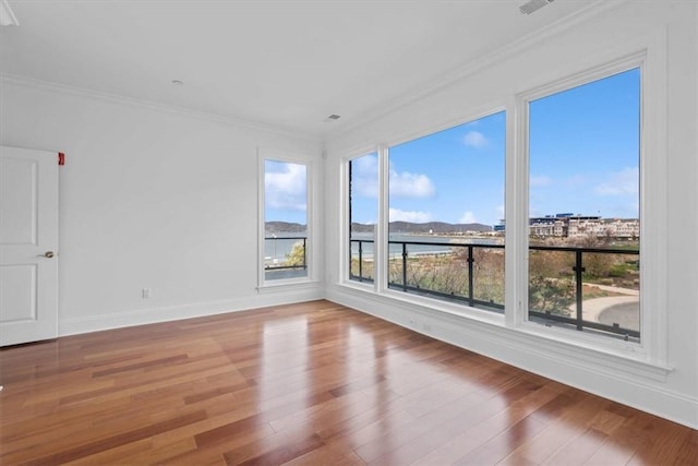 spare room with hardwood / wood-style floors, plenty of natural light, and crown molding