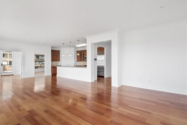 unfurnished living room with crown molding and wood-type flooring