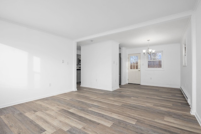 empty room featuring wood-type flooring, an inviting chandelier, and ornamental molding