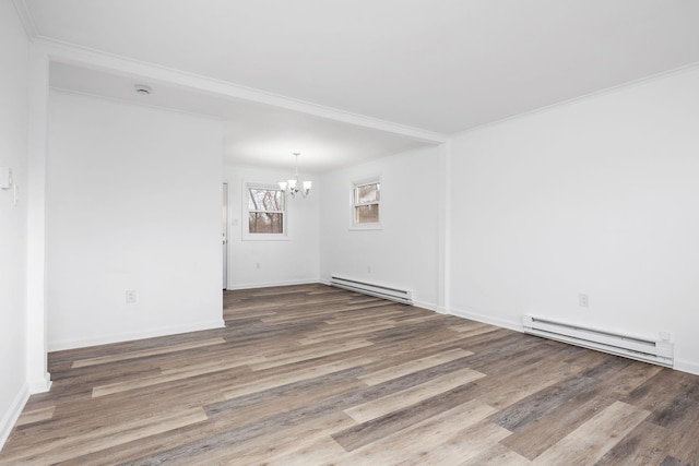 empty room with baseboard heating, an inviting chandelier, ornamental molding, and hardwood / wood-style flooring