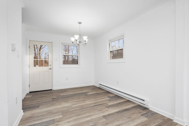 unfurnished dining area with hardwood / wood-style floors, a chandelier, ornamental molding, and a baseboard radiator