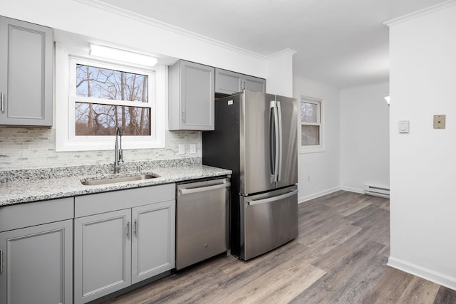 kitchen featuring gray cabinetry, backsplash, sink, baseboard heating, and stainless steel appliances