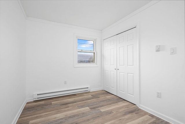 unfurnished bedroom featuring a closet, a baseboard radiator, hardwood / wood-style flooring, and ornamental molding