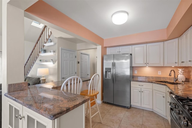 kitchen with sink, white cabinetry, dark stone countertops, appliances with stainless steel finishes, and kitchen peninsula