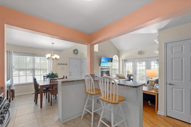 kitchen featuring a kitchen bar, kitchen peninsula, hanging light fixtures, and plenty of natural light