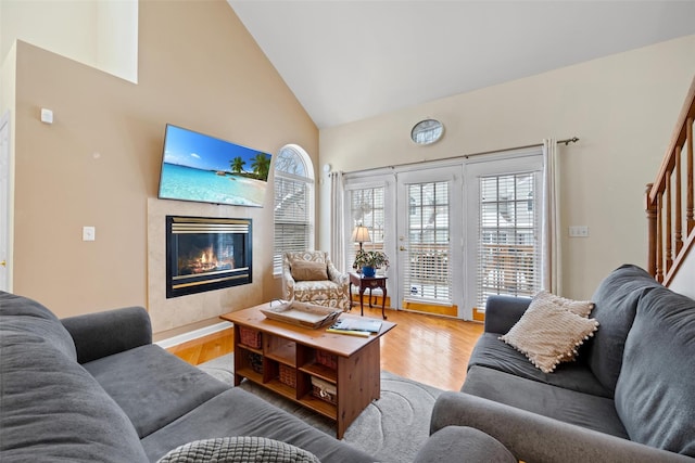 living room featuring high vaulted ceiling, light wood-type flooring, and a high end fireplace