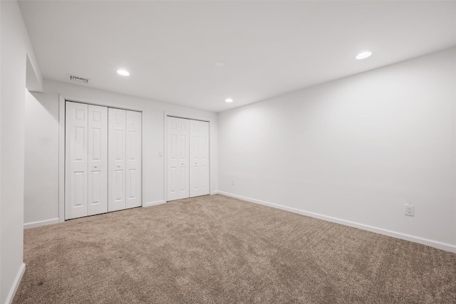 unfurnished bedroom featuring multiple closets and carpet flooring