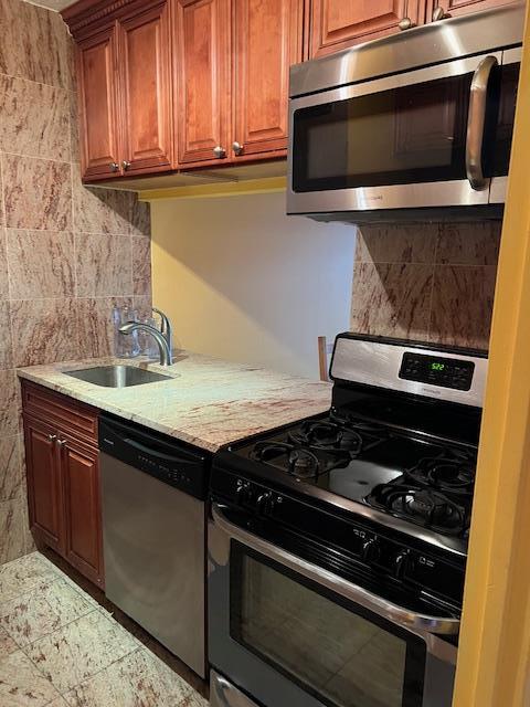 kitchen with light stone countertops, sink, and appliances with stainless steel finishes