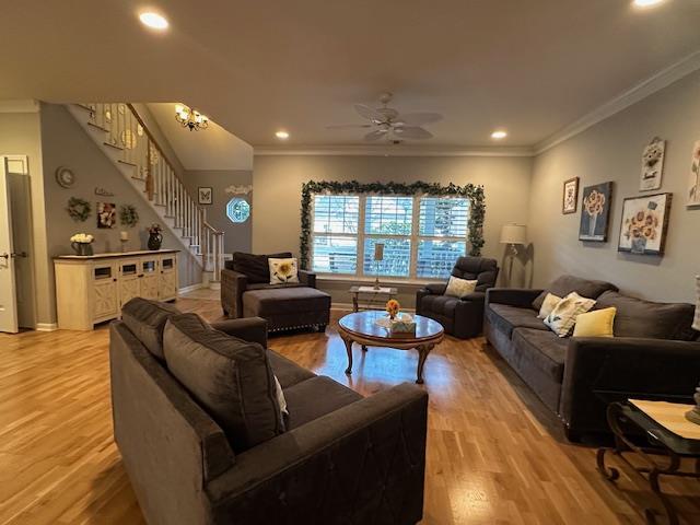 living room with crown molding, light hardwood / wood-style flooring, and ceiling fan with notable chandelier