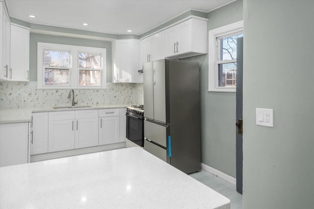 kitchen with stainless steel fridge, gas range oven, and white cabinetry