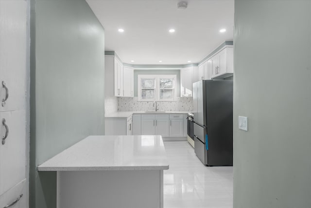 kitchen featuring kitchen peninsula, tasteful backsplash, stainless steel appliances, sink, and white cabinetry