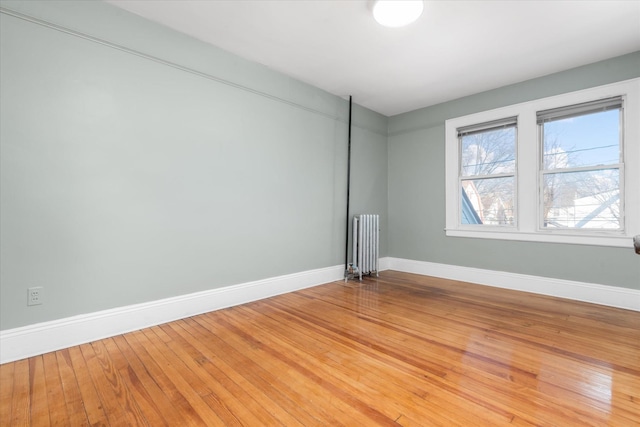 unfurnished room with radiator heating unit and wood-type flooring