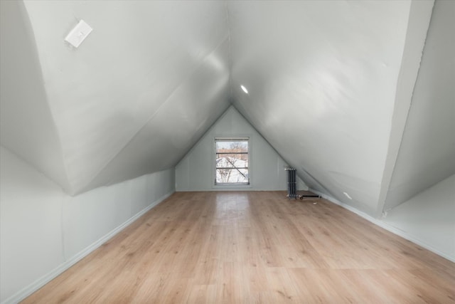 additional living space featuring light wood-type flooring and vaulted ceiling