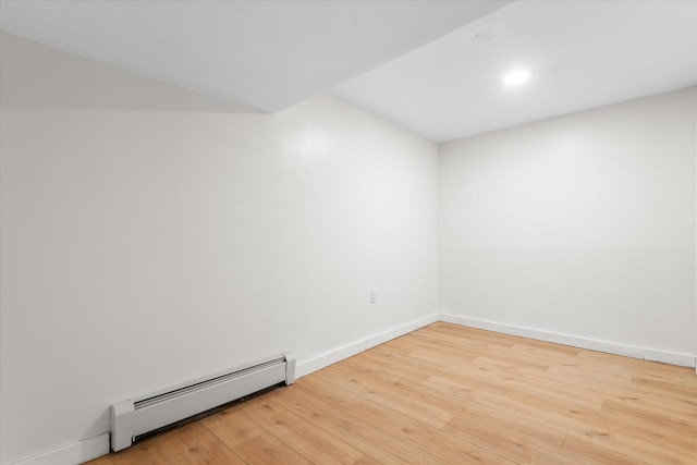 spare room with hardwood / wood-style flooring and a baseboard heating unit