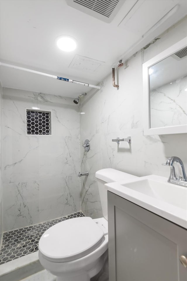 bathroom with tiled shower, vanity, and toilet