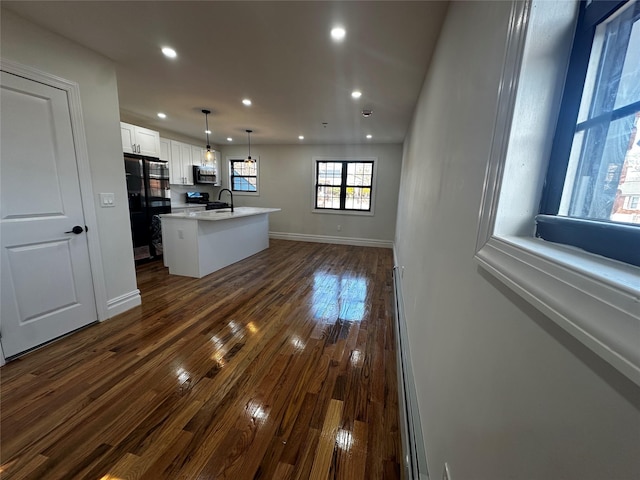 kitchen featuring black appliances, dark hardwood / wood-style flooring, white cabinetry, and a kitchen island with sink