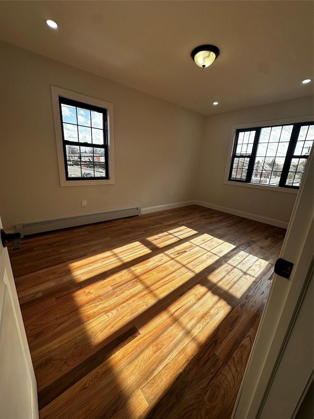 unfurnished room featuring a healthy amount of sunlight, a baseboard radiator, and light hardwood / wood-style flooring