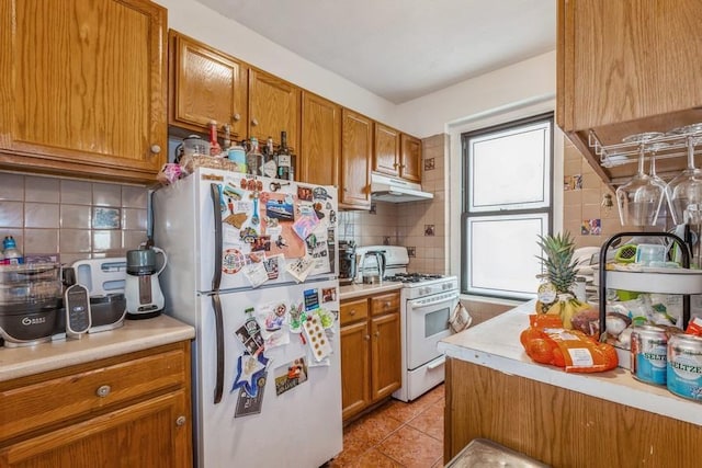 kitchen with light tile patterned flooring, white appliances, and backsplash