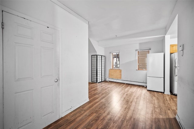 interior space with light brown cabinetry, stainless steel fridge, dark wood-type flooring, white refrigerator, and a baseboard radiator