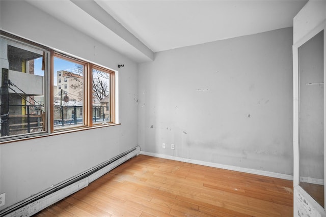 empty room featuring light hardwood / wood-style floors and a baseboard heating unit