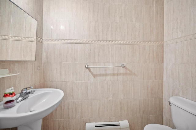 bathroom featuring toilet, tile walls, a baseboard heating unit, and sink