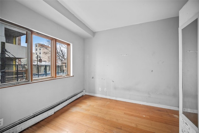 empty room with light wood-style floors, baseboards, and a baseboard radiator