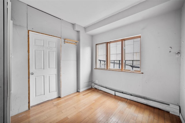 unfurnished bedroom with hardwood / wood-style flooring and a baseboard radiator