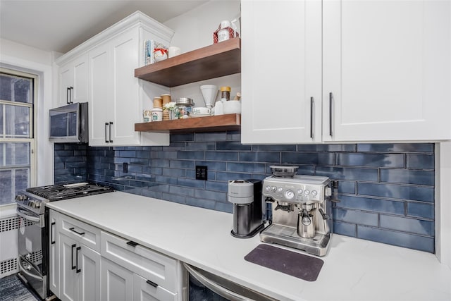 kitchen with decorative backsplash, white cabinetry, light stone countertops, and appliances with stainless steel finishes