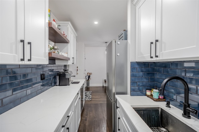 kitchen with light stone countertops, tasteful backsplash, sink, white cabinetry, and stainless steel refrigerator