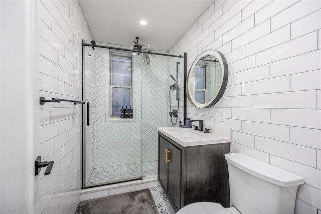 bathroom featuring vanity, toilet, a shower with door, and tile walls