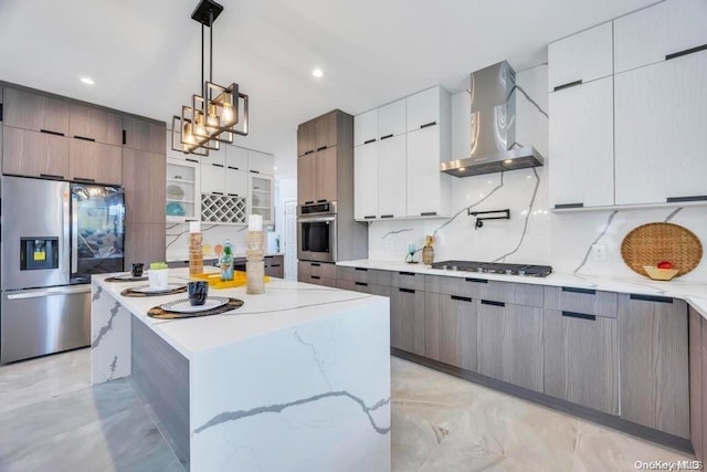 kitchen with tasteful backsplash, stainless steel appliances, wall chimney range hood, pendant lighting, and a center island