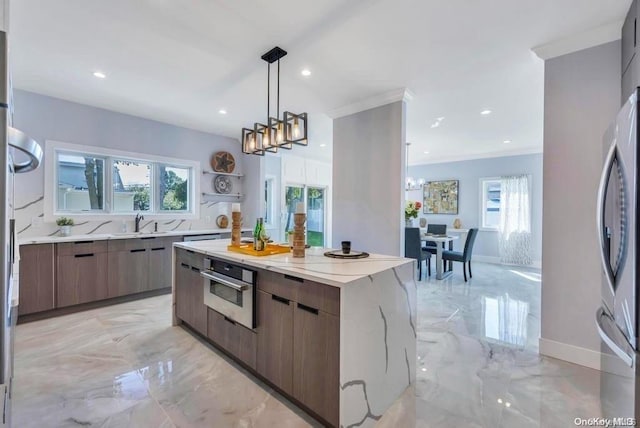 kitchen featuring ornamental molding, stainless steel appliances, sink, a center island, and hanging light fixtures