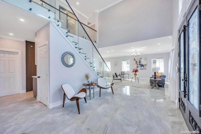 foyer with a chandelier, a high ceiling, and ornamental molding