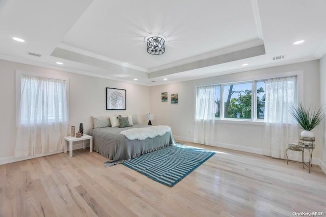 bedroom with a raised ceiling, ornamental molding, and light hardwood / wood-style flooring