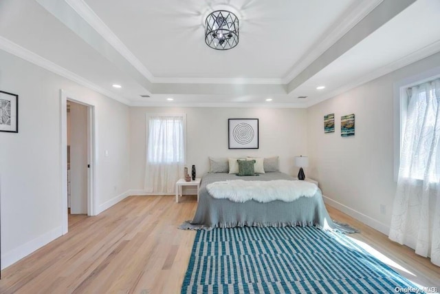 bedroom with light hardwood / wood-style floors, a raised ceiling, and crown molding