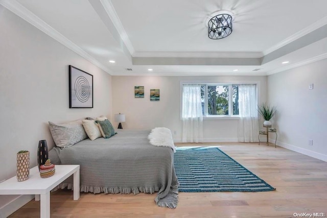 bedroom with a tray ceiling, light hardwood / wood-style flooring, and crown molding