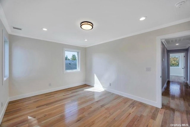 spare room with light hardwood / wood-style floors and crown molding