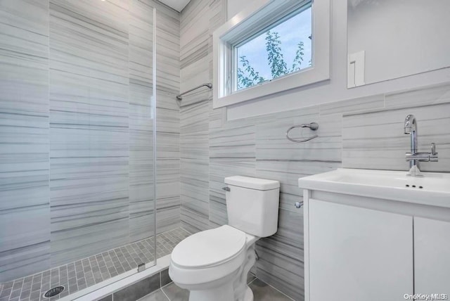 bathroom with vanity, toilet, a shower with door, and tile walls