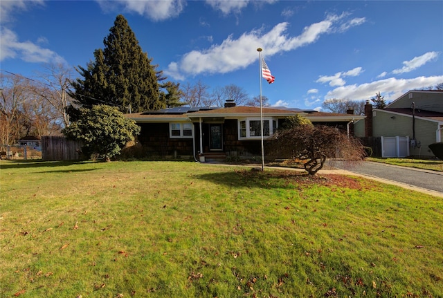 single story home featuring solar panels and a front yard