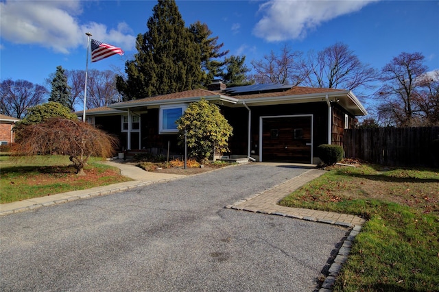 single story home featuring solar panels and a garage