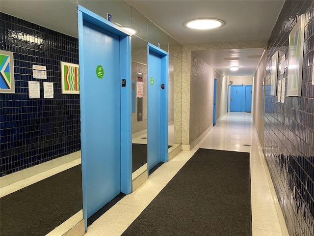 hall with elevator and tile walls