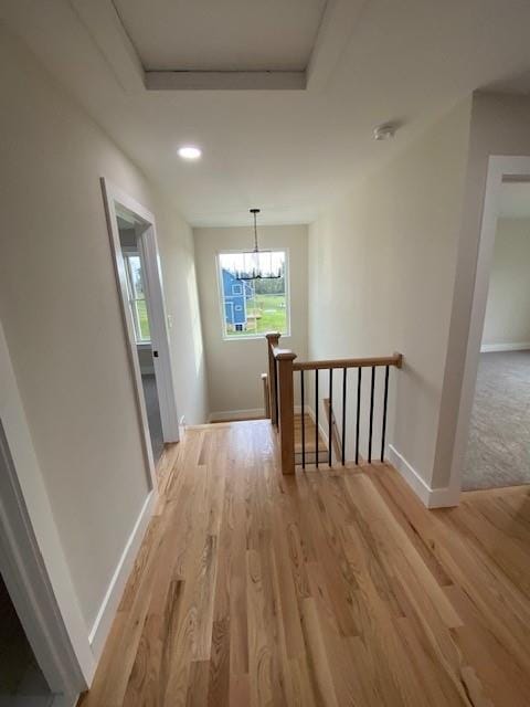 hall featuring light hardwood / wood-style floors and an inviting chandelier