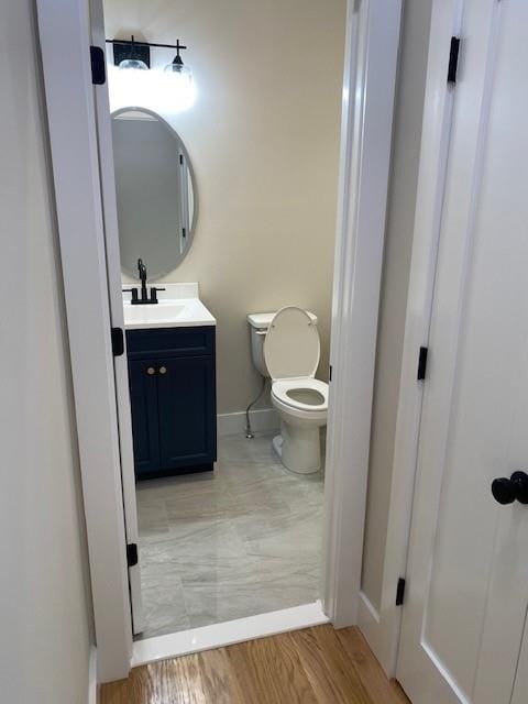 bathroom with vanity, toilet, and wood-type flooring