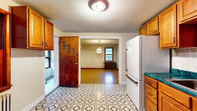 kitchen featuring pendant lighting, radiator, a notable chandelier, and white refrigerator