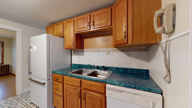 kitchen with sink, white appliances, radiator, and backsplash