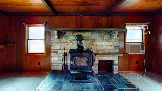 interior details with beamed ceiling, carpet flooring, a wood stove, and wood walls