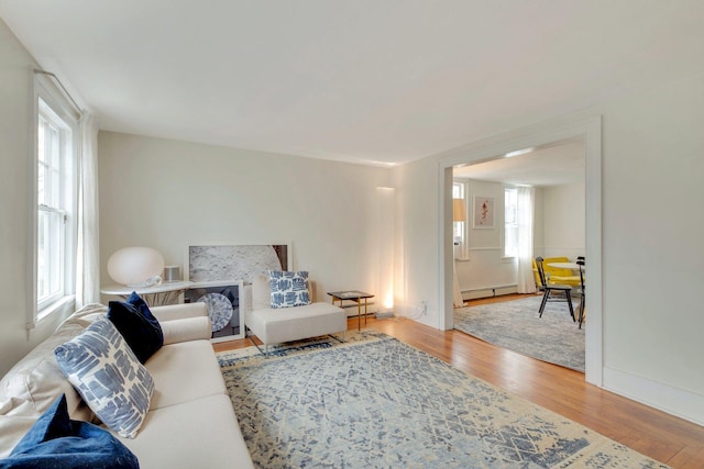 living area featuring baseboard heating, plenty of natural light, and wood finished floors