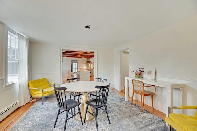 dining space featuring light wood-type flooring and a baseboard heating unit