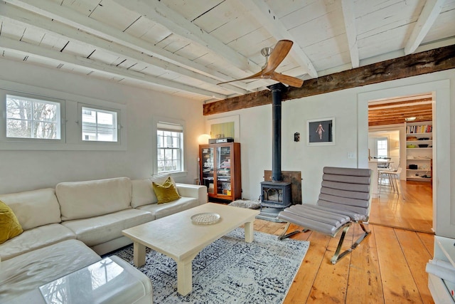 living area featuring beamed ceiling, wood ceiling, light wood-style flooring, and a wood stove