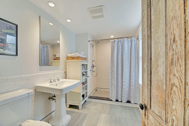 bathroom featuring tile walls, toilet, visible vents, and tiled shower